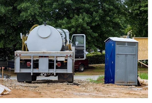 Service truck parked beside a portable restroom unit for scheduled pump-out